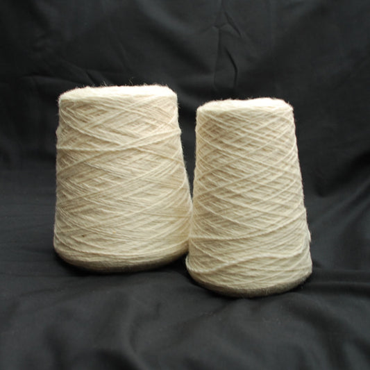 Two skeins of beige yarn on a black background