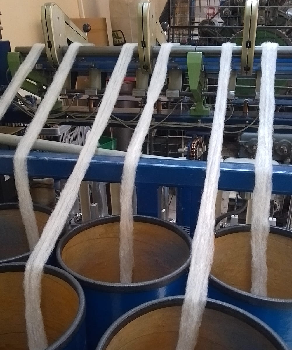 Textile production machine with yarn and spools in a factory setting