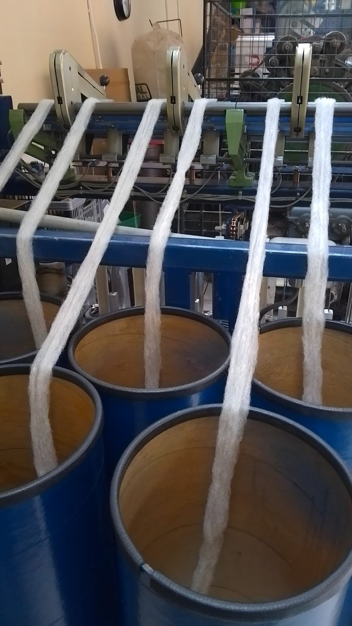 Blue barrels with white wool on a metal rack in an industrial setting